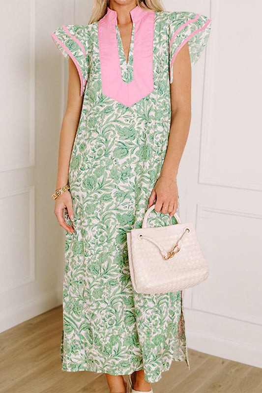 The Carly Dress, green floral with pink front panel and flutter sleeves; model carries a beige handbag.