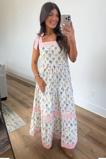 The Mia Dress floral maxi with pink striped straps, worn by a smiling woman; size chart lists S-M-L bust, waist, hem.
