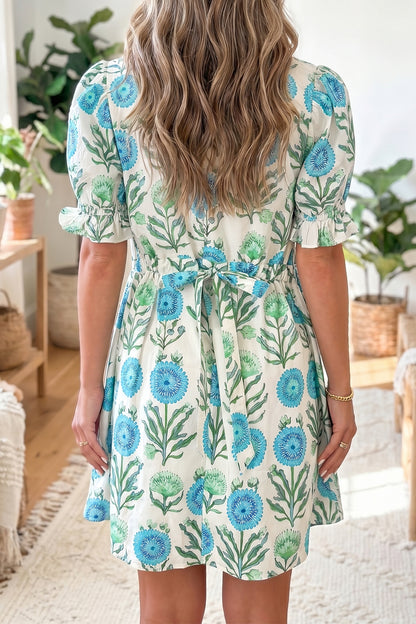 The Savannah Dress in blue floral print, back view with waist tie and puff sleeves; sizes S, M, L US 4-14.